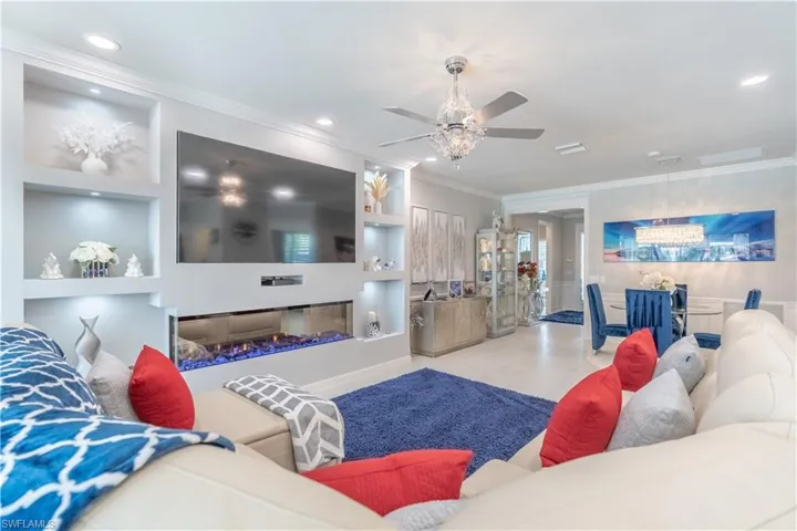 Living room featuring built in shelves, ceiling fan, and ornamental molding