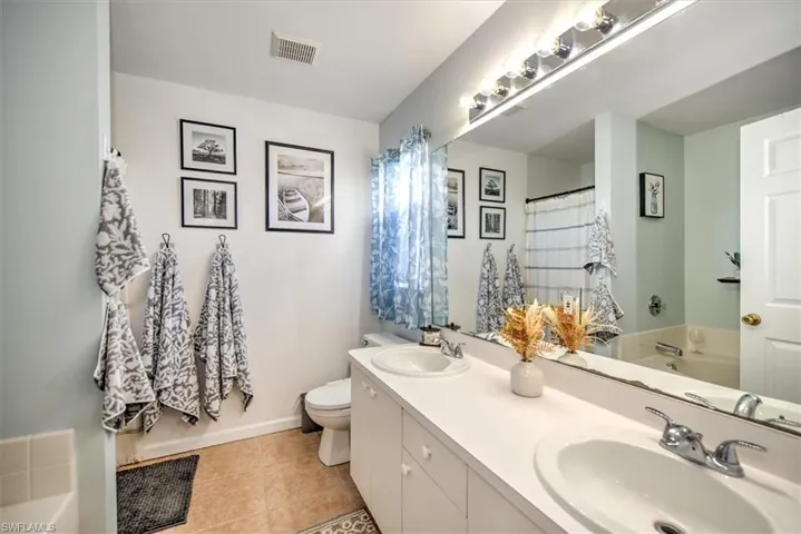 Full bathroom featuring tile patterned flooring, vanity, shower with separate bathtub, and toilet