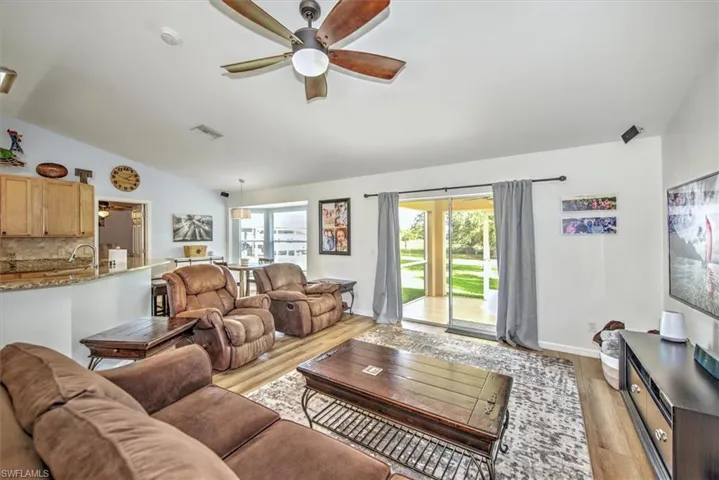 Living room featuring ceiling fan, light hardwood / wood-style flooring, vaulted ceiling, and sink