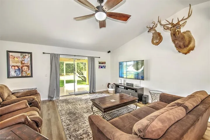 Living room with ceiling fan, high vaulted ceiling, and light hardwood / wood-style flooring
