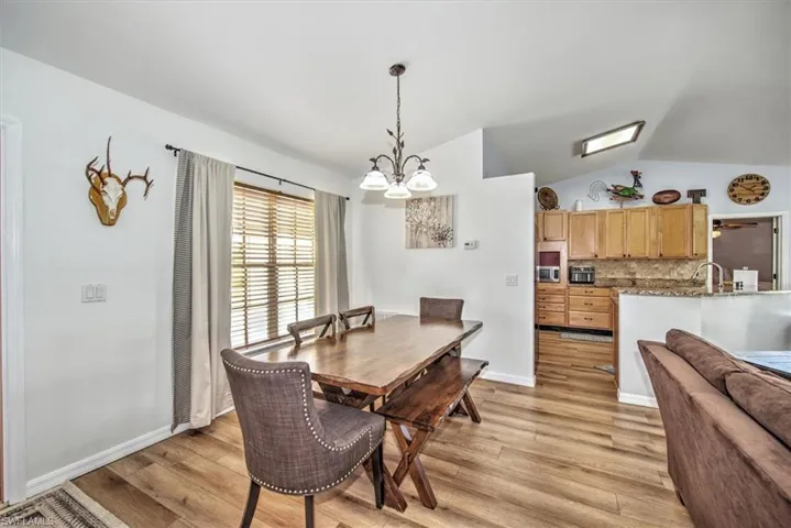 Dining area with an inviting chandelier, lofted ceiling, and light hardwood / wood-style flooring
