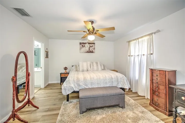 Bedroom with light wood-type flooring, ensuite bath, and ceiling fan