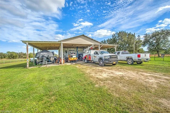View of vehicle parking with a carport and a yard