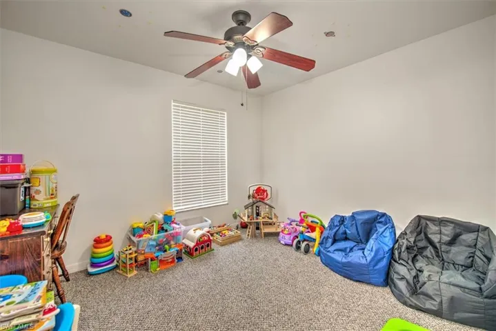 Recreation room featuring ceiling fan and carpet floors