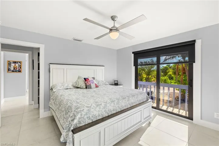 Bedroom with light tile patterned floors, access to outside, and a ceiling fan