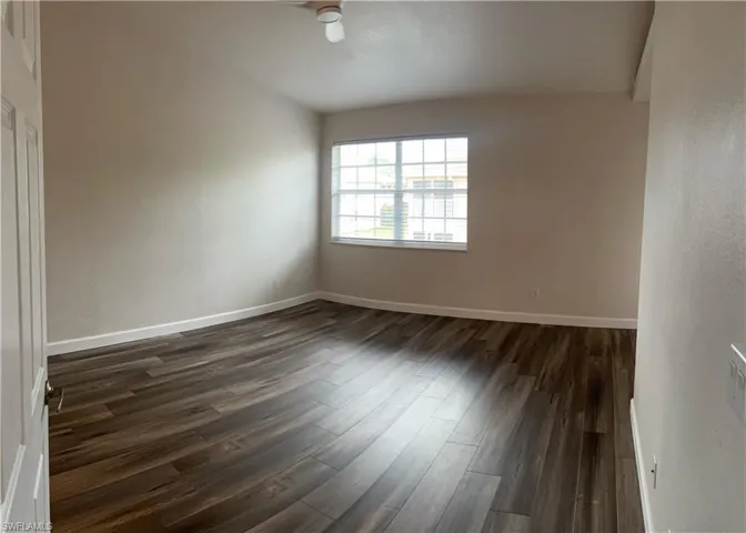 Spare room with dark wood-style floors and baseboards