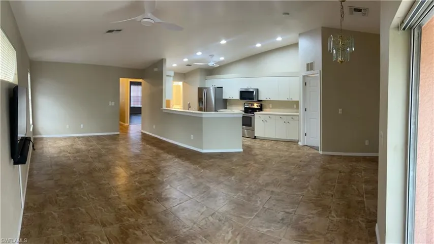 Kitchen with stainless steel appliances, a ceiling fan, vaulted ceiling, white cabinets, and a peninsula