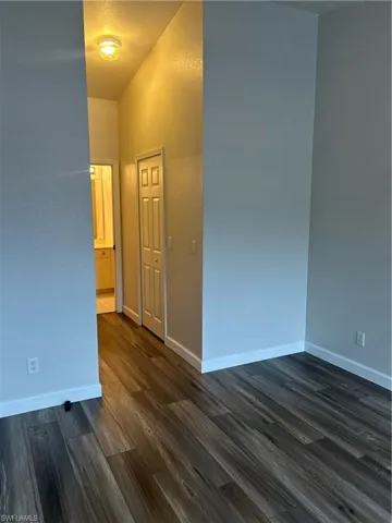 Spare room featuring dark wood-style flooring and baseboards