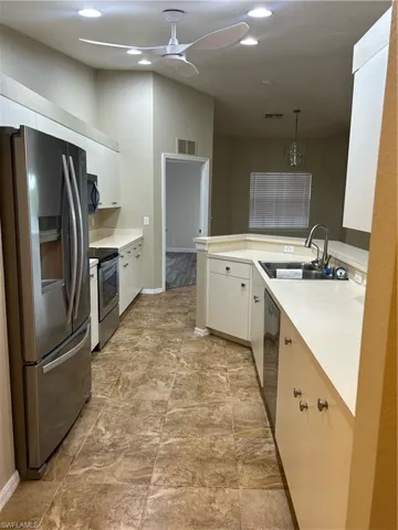 Kitchen featuring refrigerator, stove, a peninsula, light countertops, and white cabinetry