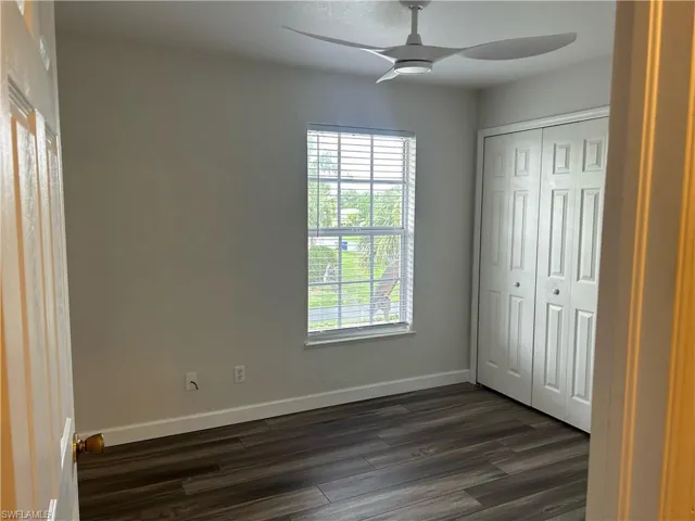 Unfurnished bedroom featuring dark wood-style floors, a closet, and ceiling fan