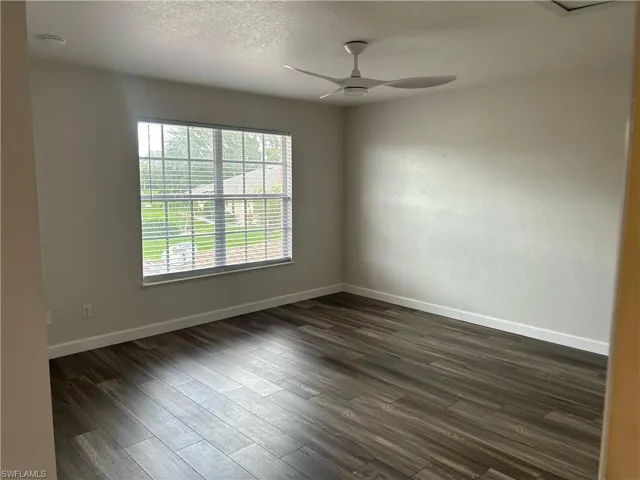Unfurnished room with ceiling fan, dark wood-type flooring, and a textured ceiling