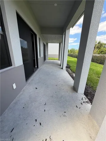 The property features a covered patio with a concrete floor, offering views of a grassy area