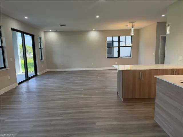 This open-concept living area features light-colored plank flooring, recessed lighting, and sliding glass doors that open to an outdoor patio