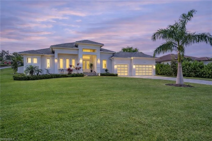 Prairie-style home featuring driveway, a front lawn, stucco siding, and a garage