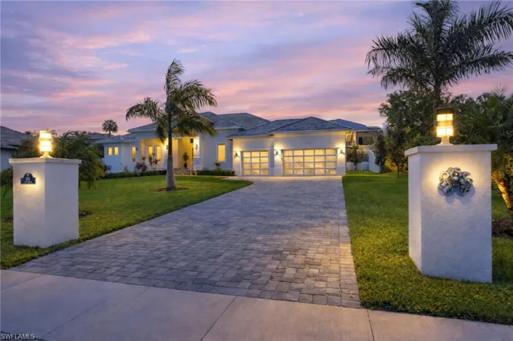 View of front facade featuring decorative driveway, stucco siding, an attached garage, and a yard