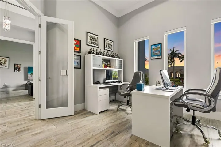 Office featuring light wood-type flooring, ornamental molding, and a high ceiling