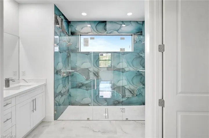 Full bath with vanity, a marble finish shower, and recessed lighting