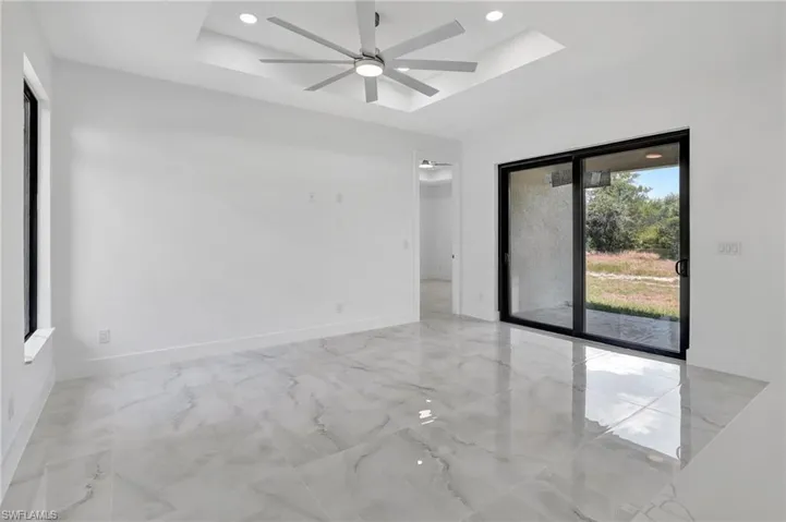 Unfurnished room with a raised ceiling, a ceiling fan, light marble finish floors, and recessed lighting