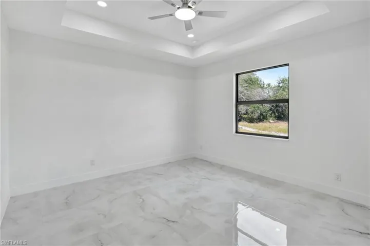 Spare room featuring a raised ceiling, recessed lighting, and a ceiling fan
