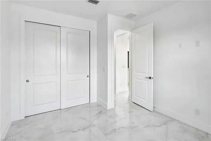 Unfurnished bedroom with a closet and light marble finish flooring