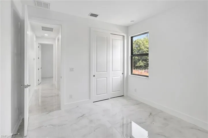 Unfurnished bedroom featuring light marble finish flooring and a closet