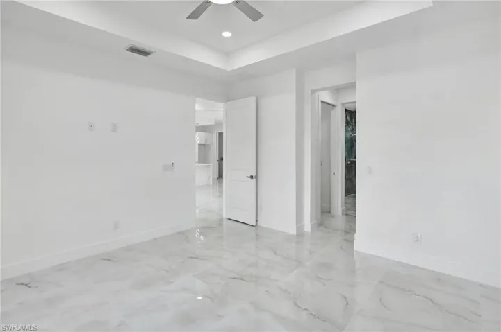 Unfurnished bedroom featuring a ceiling fan, a raised ceiling, and recessed lighting