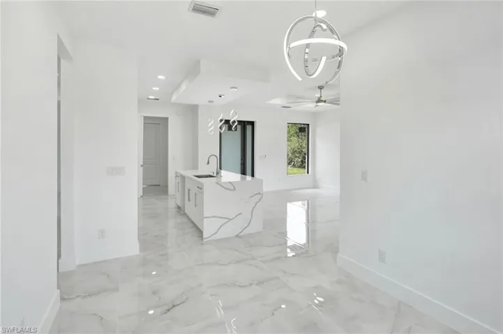 Empty room featuring a chandelier, light marble finish floors, and ceiling fan