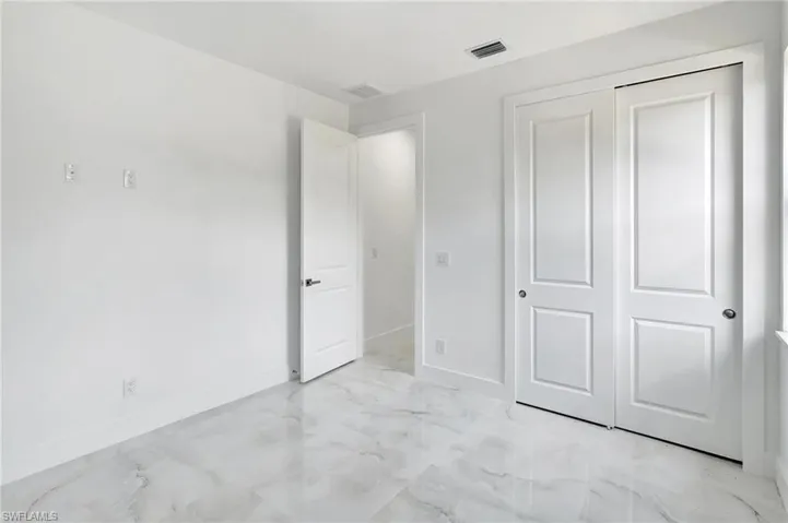 Unfurnished bedroom with a closet and light marble finish flooring