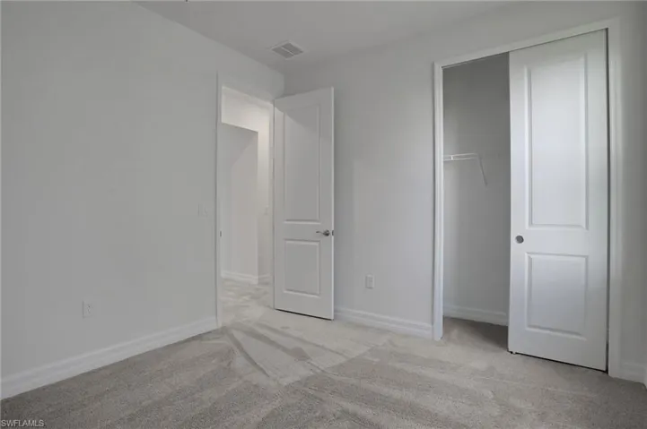 Unfurnished bedroom featuring light carpet and a closet