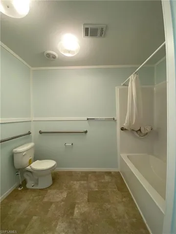 Bathroom featuring shower / tub combo, a textured ceiling, and toilet