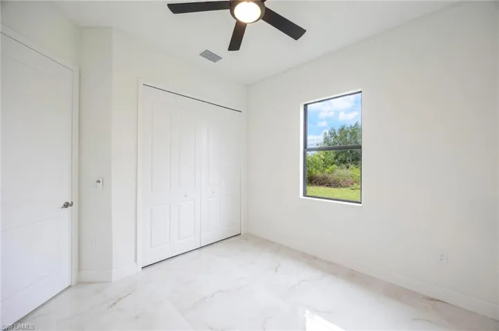 Unfurnished bedroom with a closet, ceiling fan, and light tile floors