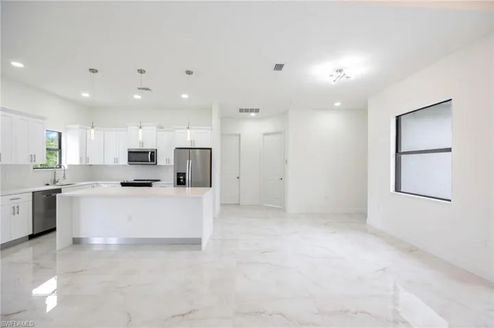 Kitchen featuring a center island, light tile floors, pendant lighting, and appliances with stainless steel finishes