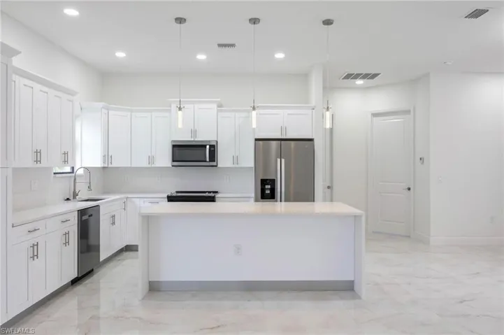 Kitchen with a center island, sink, tasteful backsplash, and appliances with stainless steel finishes