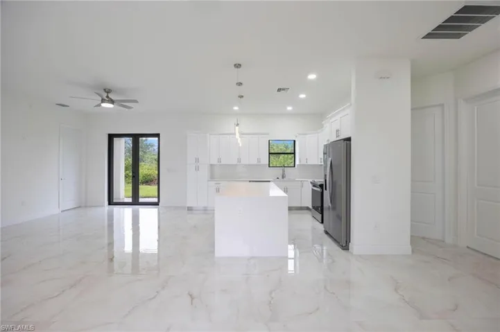 Kitchen featuring a kitchen island, stainless steel appliances, light tile flooring, and hanging light fixtures