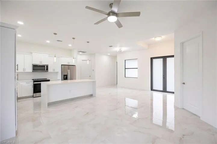 Kitchen featuring a center island, hanging light fixtures, stainless steel appliances, ceiling fan, and light tile floors
