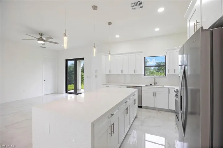 Kitchen featuring ceiling fan, tasteful backsplash, a center island, sink, and appliances with stainless steel finishes