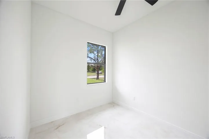 Tiled spare room featuring ceiling fan