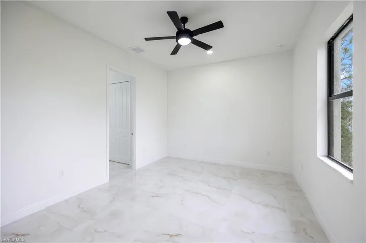 Tiled empty room featuring ceiling fan