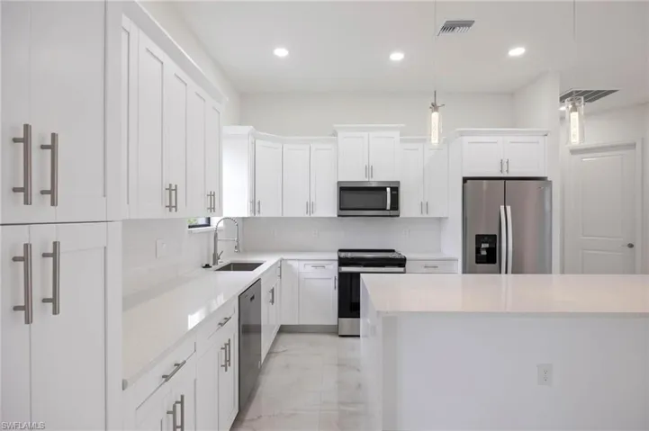 Kitchen with stainless steel appliances, pendant lighting, backsplash, light tile floors, and sink