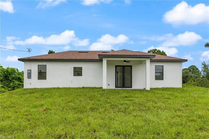Rear view of house with a yard and ceiling fan