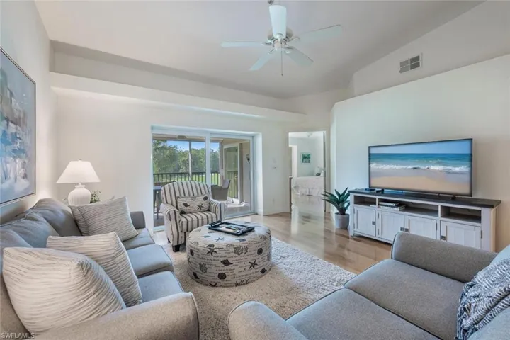 Living area with light wood-style flooring, lofted ceiling, and ceiling fan