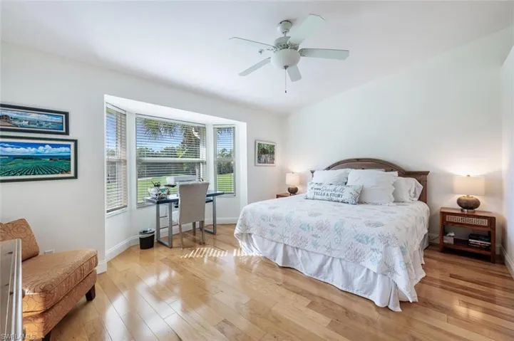 Bedroom with light wood-style flooring, ceiling fan, and an office area