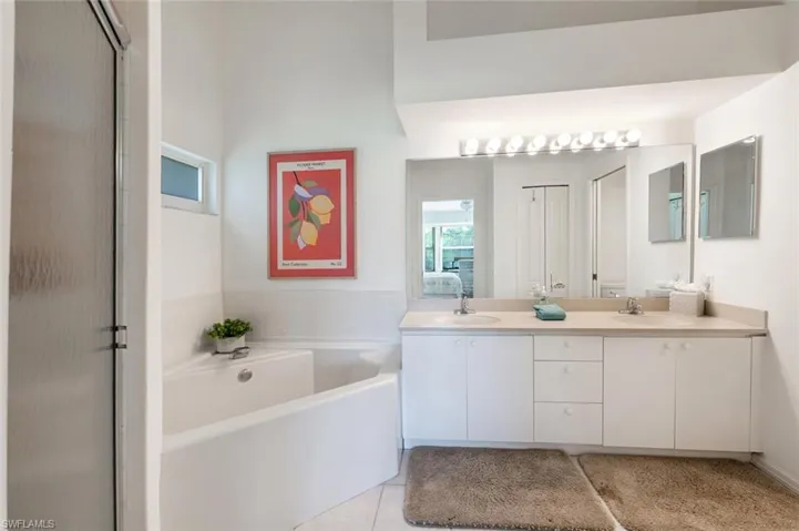 Bathroom featuring double vanity, a bath, tile patterned flooring, and a shower with door