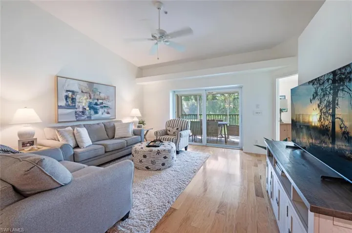 Living room with light wood-style floors, ceiling fan, and lofted ceiling