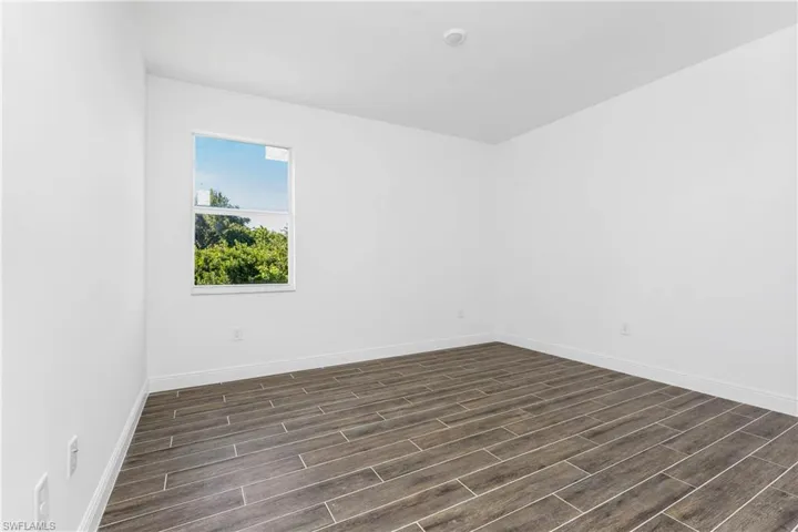 Unfurnished room featuring wood finish floors and baseboards