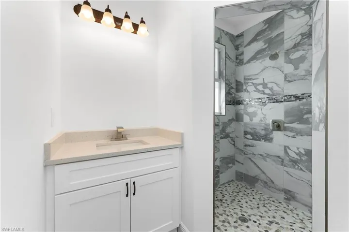 Bathroom with vanity and a marble finish shower