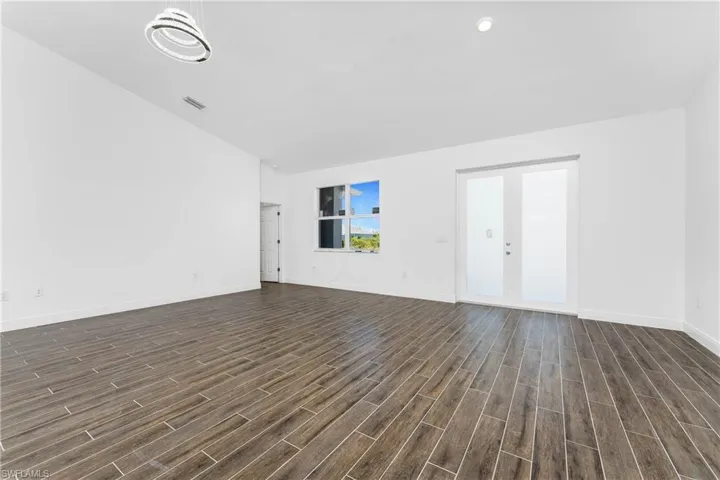 Unfurnished living room with wood tiled floors and lofted ceiling