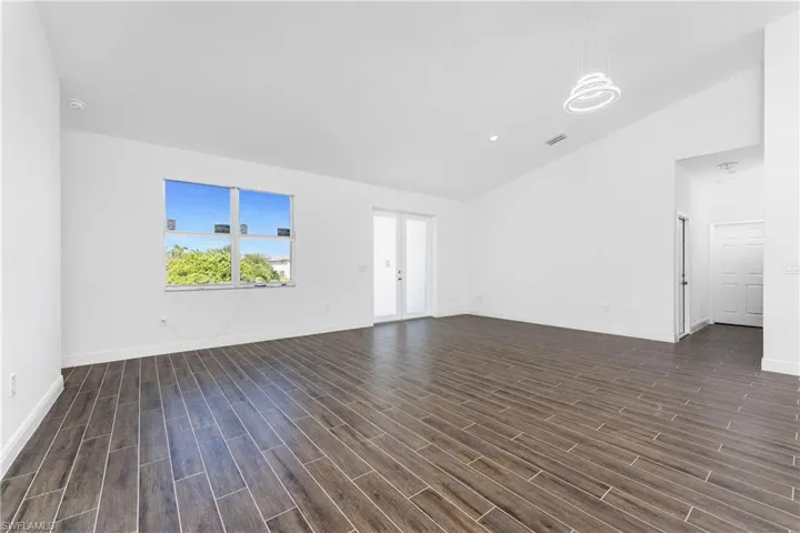 Unfurnished living room featuring lofted ceiling, wood finish floors, and recessed lighting