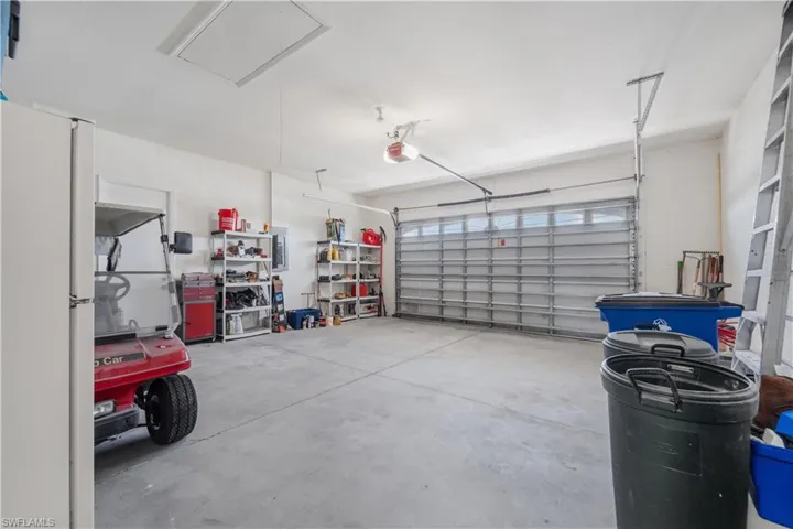 Garage featuring a garage door opener and freestanding refrigerator