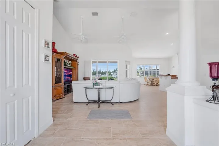 Living room with decorative columns, a ceiling fan, and high vaulted ceiling